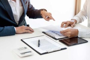 Family reviews insurance documents at a kitchen table beside a home inventory notebook and calculator.